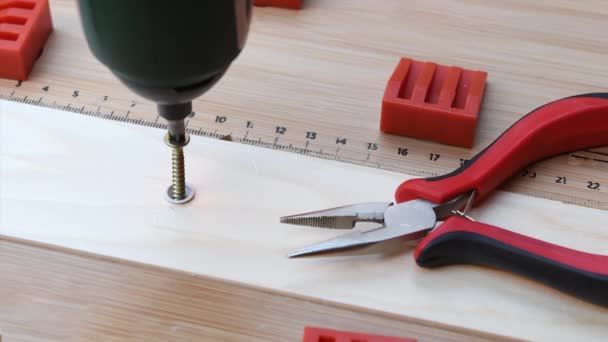 Electric screwdriver by screwing a screw into a piece of wood together with pliers - Footage, Video