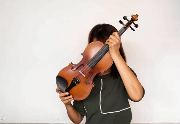 Скрипка поднималась, чтобы закрыть лицо леди, показать переднюю часть и детали акустического инструмента - Фото, изображение