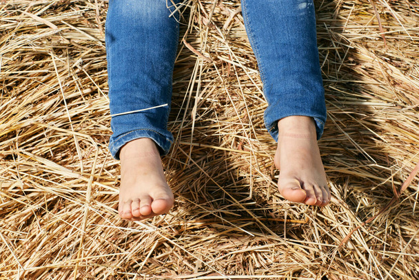voeten van een klein kind in het hooi - Foto, afbeelding