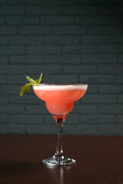 Pinkfarbener Cocktail im Glas auf einem Holztisch vor einer Ziegelwand. Fotos für Speisekarten von Restaurants, Cafés und Bars - Foto, Bild