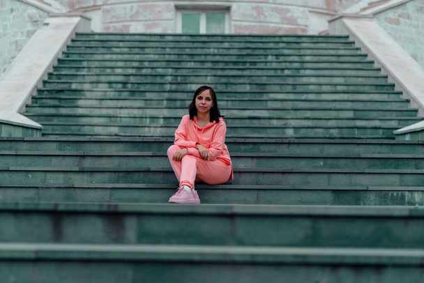 Dorosła kobieta siedząca na schodach Pałacu. - Zdjęcie, obraz