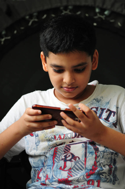 Мальчик, увлекающийся игрой на мобильном телефоне - Фото, изображение