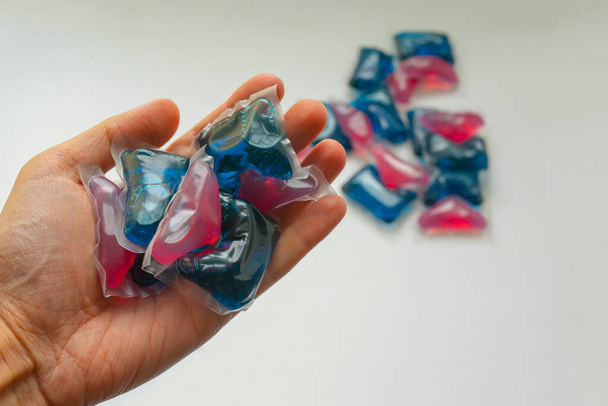 cápsulas de gel azul y rojo para un lavado delicado en la palma de la mano de un hombre. Cápsulas para lavar ropa y ropa - Foto, Imagen