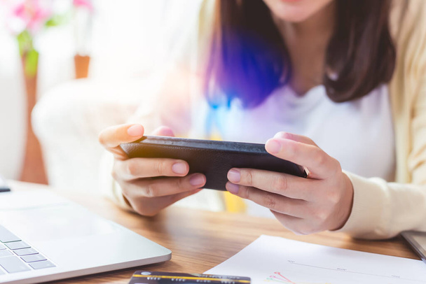 Aasialainen nainen pelaa online-peli sovellus tai chattailuun tekstiviestin ystävän kanssa älypuhelimella. Vaara sininen valo voi vahingoittaa silmiä ja voi olla ikään liittyvä silmänpohjan rappeuma sinisestä valosta - Valokuva, kuva