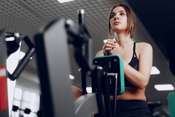 Young beautiful woman training her arms in a gym apparatus - Фото, зображення