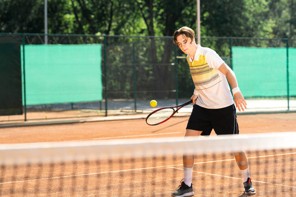 若いテニス選手がボールを打つ - 写真・画像