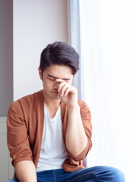 Young asian man rubbing his eyes - Foto, afbeelding