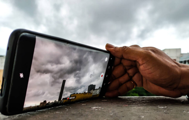 Человек записывает движение облаков со смартфона или мобильного телефона. - Фото, изображение