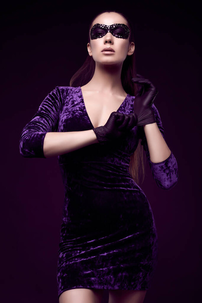 Портрет чарівної елегантної брюнетки в красивій фіолетовій сукні та блискітках маска рукавички на чорному тлі в студії
 - Фото, зображення