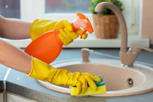 Womans hands in yellow gloves cleaning counter top in kitchen - Foto, Imagen
