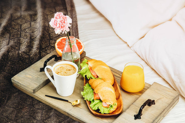  Breakfast in bed on a wooden tray. Coffee, orange juice, croissants and grapefruit. - Fotó, kép