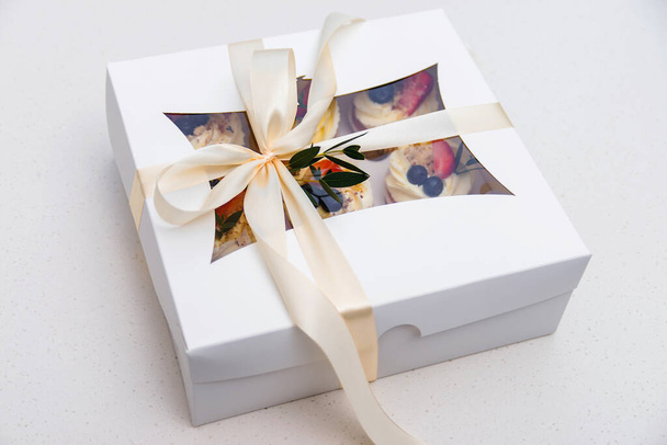 Gift box with tasty cupcakes. Present box full of fruit cupcakes. Birthday party. Easter or christmas holidays celebrate. Holidays cupcakes with strawberry and blueberry. Cupcake packaging. Delivery. - Photo, Image