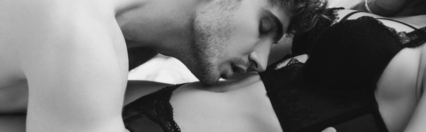 cultura panorâmica de homem sem camisa beijando mulher sedutora em roupa interior relaxante na cama em casa
 - Foto, Imagem
