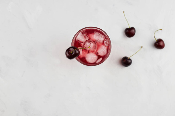 Cherry cocktail with ice on a light background. Top view, with copy space - 写真・画像