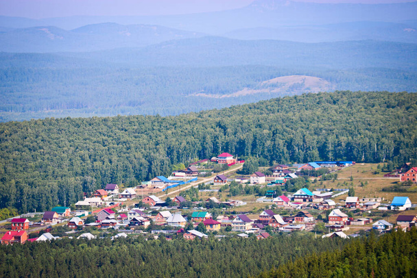 View of the village and pine forests from the Chashkovsky ridge. Ural mountains. Eco-tourism and hiking concept. - Photo, Image
