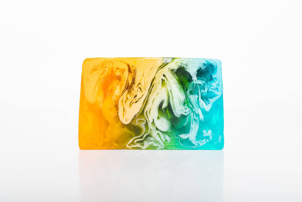 Jabón cosmético hecho a mano. Desbordamientos de turquesa a naranja verde y amarillo. - Foto, Imagen