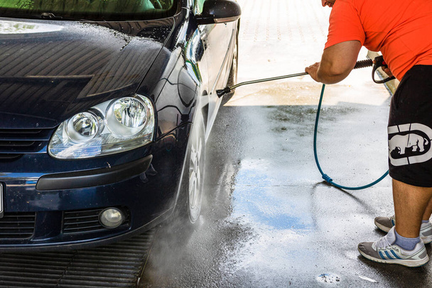 Омивання і прибирання автомобіля в автомийці. Миття автомобіля з використанням води високого тиску в Бухаресті (Румунія, 2020 рік). - Фото, зображення