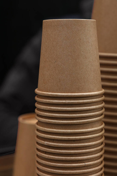 Close up stack of brown disposable kraft paper cups on coffee machine, low angle view - Foto, Imagem