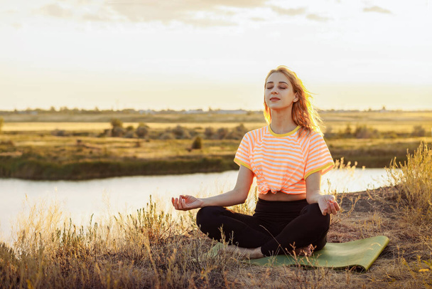 Young blonde woman making yoga outdoors.  - 写真・画像