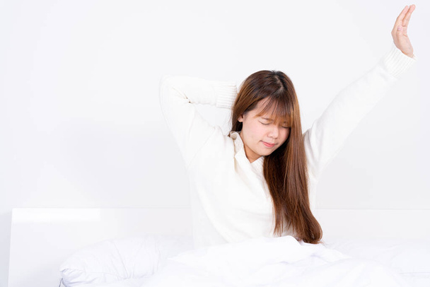 Genç Asyalı kadın rahat yatağından kalktıktan sonra yatakta geriniyor. Sağlık hizmeti tıbbi veya günlük yaşam konsepti. - Fotoğraf, Görsel