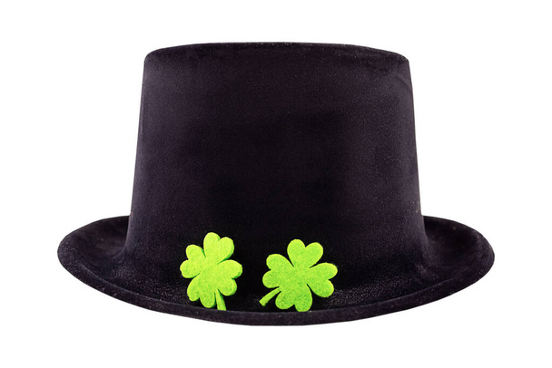 St. Patrick schwarzer Hut mit einem Paar grüne Klee Feiertagssymbol verziert liegt auf einem isolierten Hintergrund Design - Foto, Bild