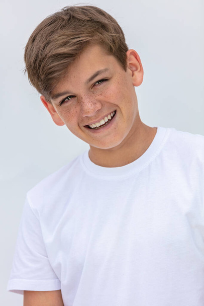 White background studio portrait of a smiling happy boy teenager teen male child with perfect teeth wearing a white t-shirt - Foto, Imagem