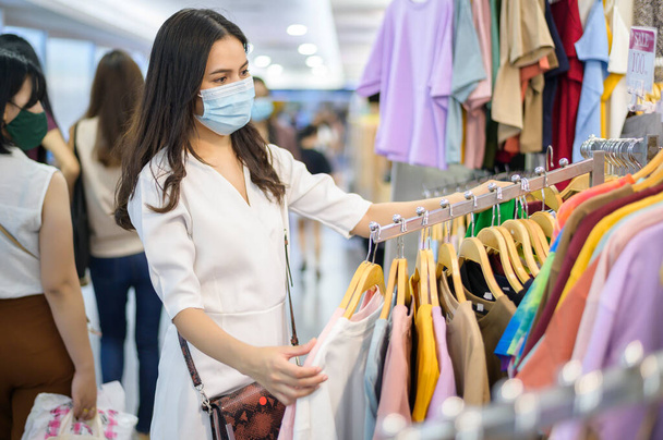 woman with face mask is shopping clothes in Shopping center woman with face mask is shopping clothes in Shopping center . - Foto, Imagen