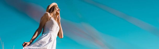 Mavi gökyüzüne karşı beyaz elbiseye dokunan genç kadının seçici odak noktası, panoramik konsept - Fotoğraf, Görsel