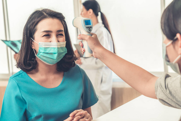 Receptionist en gast dragen gezichtsmasker aan de receptie tijdens een gesprek in kantoor of ziekenhuis. Covid 19 en coronavirus bescherming en beschermende beleid concept . - Foto, afbeelding