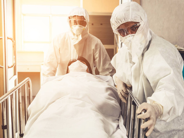 Ensihoitaja ja lääkäri siirtävät potilaan sairaalan ensiapuun. Lääkäri pukeutuu suojapuku ja kasvonaamio käsite sepelvaltimovirus ja covid 19 suojelu ja karanteeni . - Valokuva, kuva