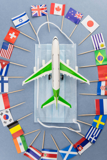 Safe travels concept. Plane with surgical medical mask. Safety flight and travel during quarantine and lockdown. Passenger airplane on national flag background. Flight permit. - Foto, immagini