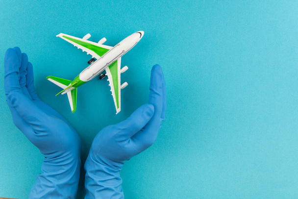 Safe travels concept. Plane in hands in medical gloves. Safety flight and travel during quarantine and lockdown. - Fotografie, Obrázek