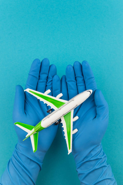 Veilig reizen concept. Vliegtuig in handen met medische handschoenen. Veiligheidsvlucht en reis tijdens quarantaine en vergrendeling. - Foto, afbeelding