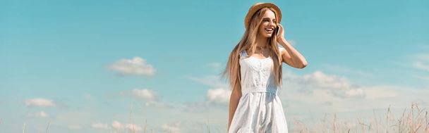 ιστοσελίδα κεφαλίδα της ξανθιάς γυναίκας σε ψάθινο καπέλο και λευκό φόρεμα μιλάμε για smartphone κατά του μπλε ουρανού - Φωτογραφία, εικόνα