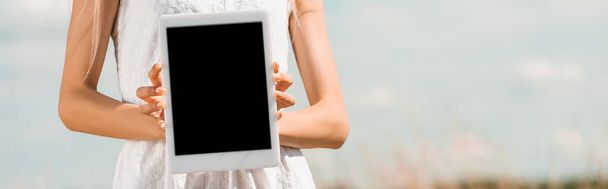 Mavi gökyüzüne karşı boş ekranlı dijital tablet gösteren bir kadın görüntüsü, yatay görüntü - Fotoğraf, Görsel