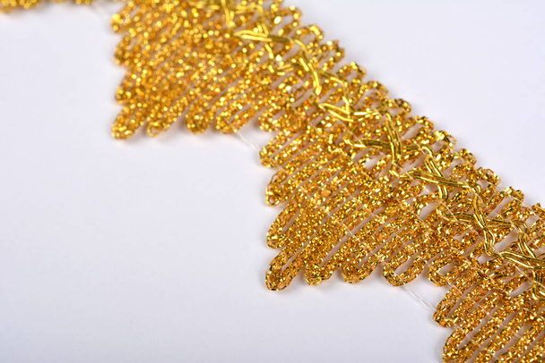 Fonott csipke készült Luxus fém arany zsinór fehér háttérrel. dekoráció a karnevál és tánc ruhák jelmezek. Karácsonyi textúra. banner honlaphoz - Fotó, kép