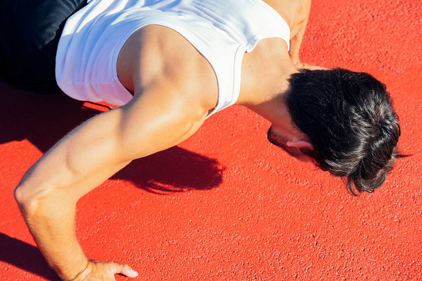 close-up of an unrecognizable sportsman doing push-ups on a red floor, concept of urban sport and healthy lifestyle - Valokuva, kuva