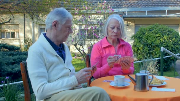 Starší pár relaxační venkovní hrací karty a dělat snídani - Záběry, video