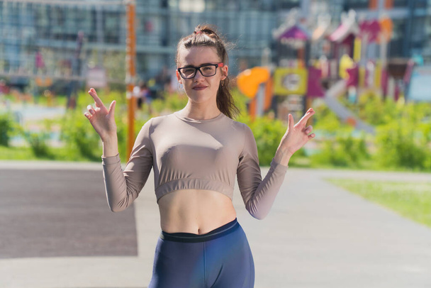 Sporting stylish girl crossed her fingers. The concept is hoping for a miracle. Young woman in sportswear top short with pants - Foto, immagini