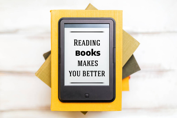 Lezen en kennis. E-book reader ligt bovenop een stapel boeken op een houten achtergrond. Plat gelegd. Begrip onderwijs en elektronische gadgets. - Foto, afbeelding
