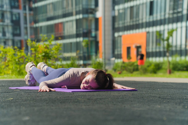 Sporting a tired young girl lies face down on a yoga mat. The concept of weakness after strength training, - Φωτογραφία, εικόνα