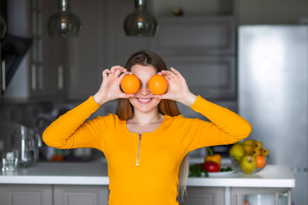 少女は両手に柑橘類のグレープフルーツの半分を持っていて目を覆っている。健康的な食事. - 写真・画像