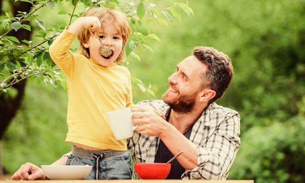 family dinner time. father and son eating outdoor. happy fathers day. Little boy with dad eat cereal. Morning breakfast. Vegetarian diet. healthy food and dieting. Dairy products. Family bonds - Foto, Imagen