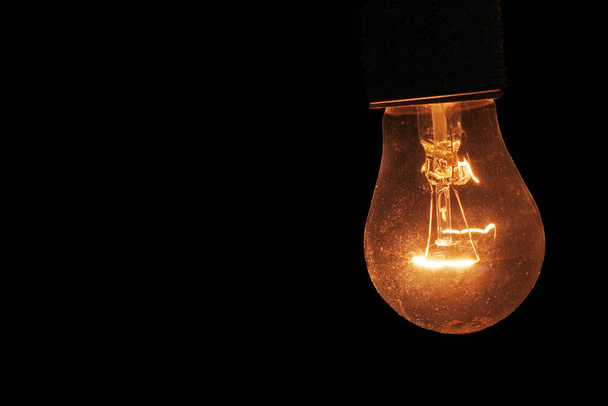 lâmpada incandescente queimando amarelo no escuro da noite com lugar para texto
 - Fotografia, imagem