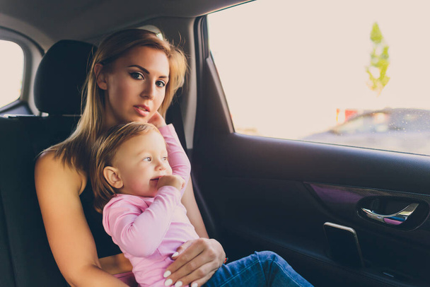 Little baby toddler girl looks out of the car window with her mom. - Foto, imagen