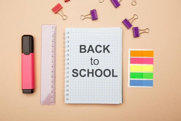 School kantoorbenodigdheden op roze achtergrond en notebook met TERUG TO SCHOOL - Foto, afbeelding