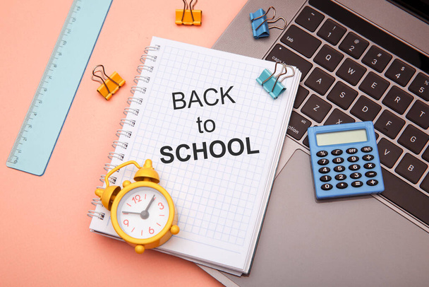 School kantoorbenodigdheden op roze achtergrond en notebook met TERUG TO SCHOOL - Foto, afbeelding