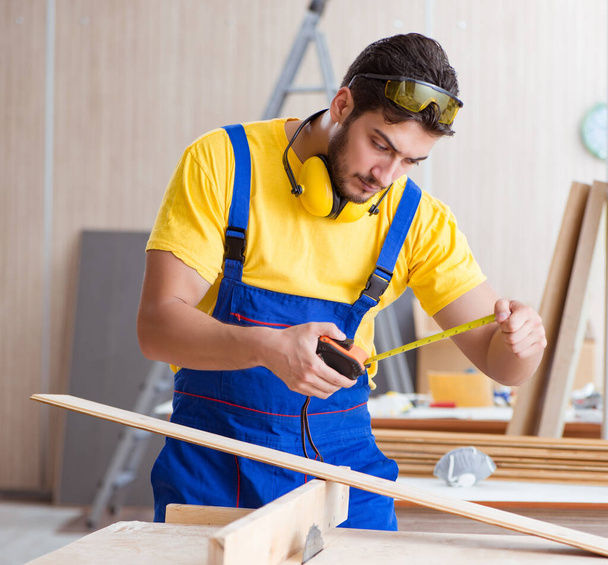 Young repairman carpenter working cutting wood on circular saw - Zdjęcie, obraz