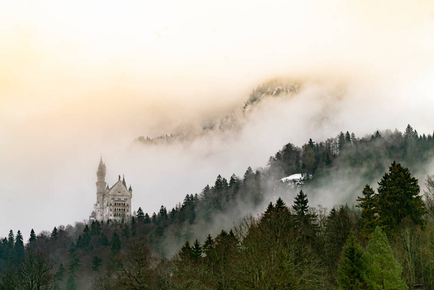 Magnifique vue sur le château de Neuschwanstein dans les Alpes bavaroises depuis le pont perdu dans le brouillard avec des nuages - Photo, image