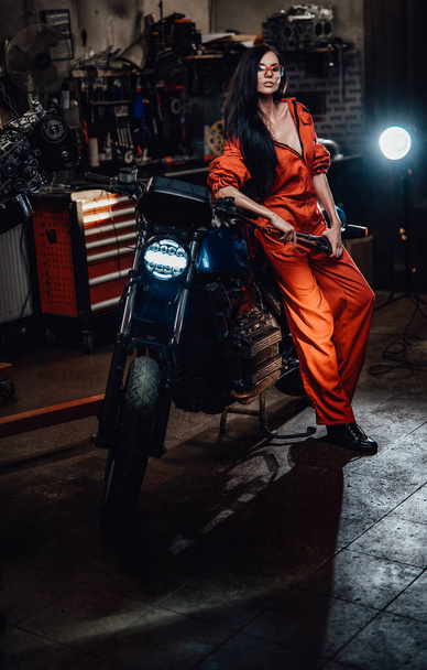 Sexy Brünette lehnt auf einem schwarzen Motorrad - Foto, Bild